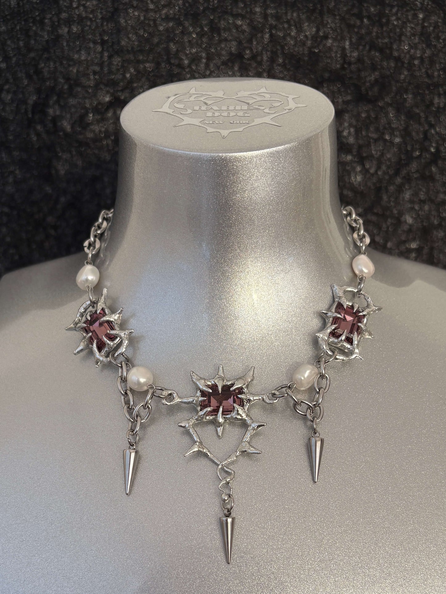 The Midnight Candelabrum Necklace is a sculptural statement piece inspired by gothic candleholders and nocturnal ritual objects. Handcrafted by RABIES DOG, this necklace carries a dark, altar-like presence—designed to be worn as both adornment and symbol.